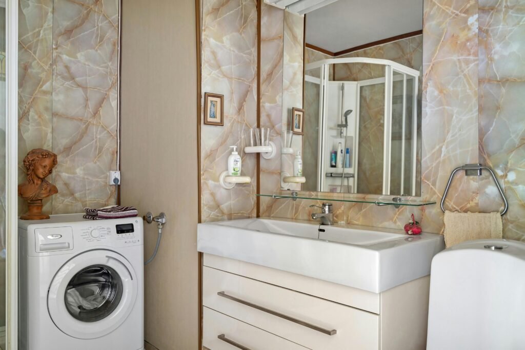 Contemporary bathroom featuring marble walls, elegant sink, and a washing machine.
