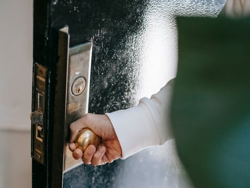 High angle of crop unrecognizable person holding round shaped handle while opening door at home