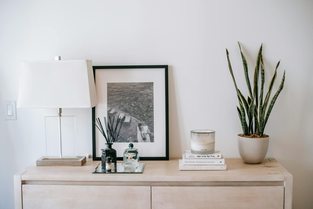 Photography near lamp and incense sticks in decorative bottle near candle on pile of books on commode