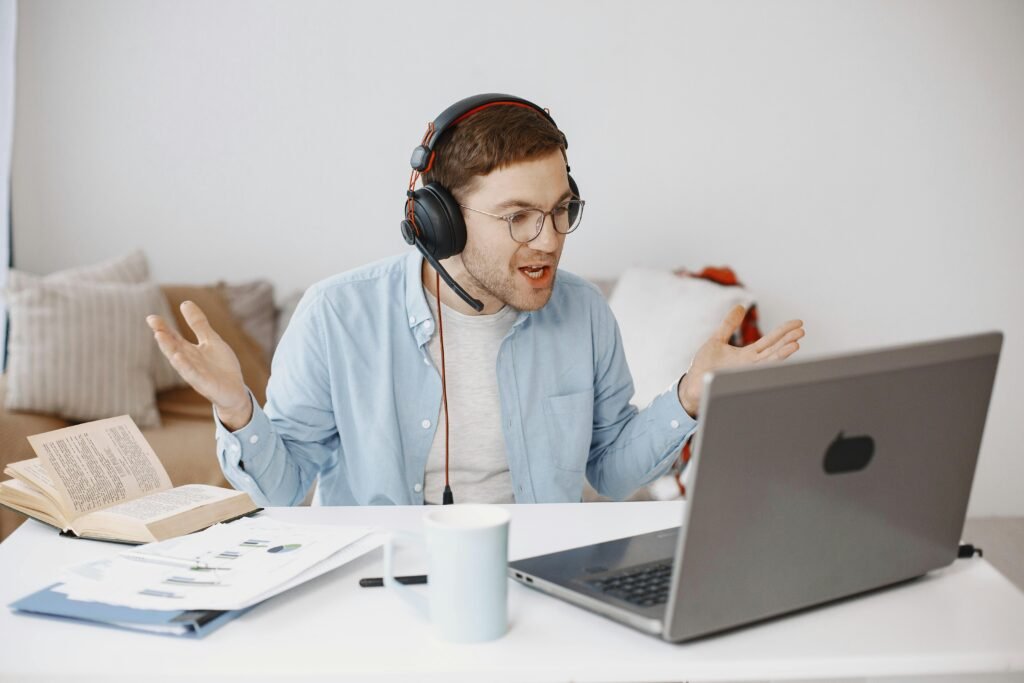 Adult man expressing frustration during an online meeting in home office setting.