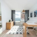 How to Make a Small Airbnb Feel Bigger Wooden table and drawer placed in room with big window and wall decorated with pictures in light room with mirror